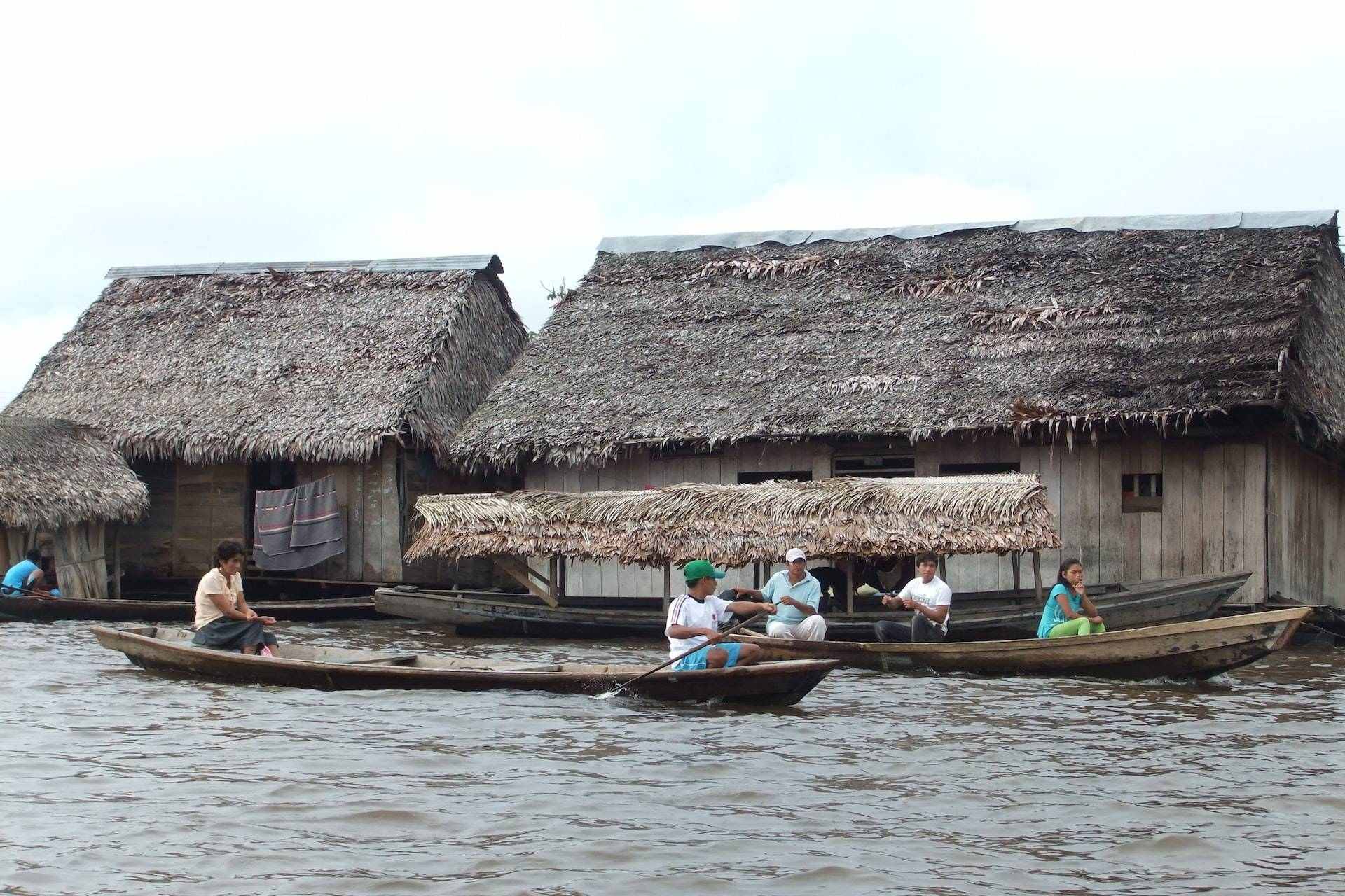 people riding on boat near brown wooden house during daytime