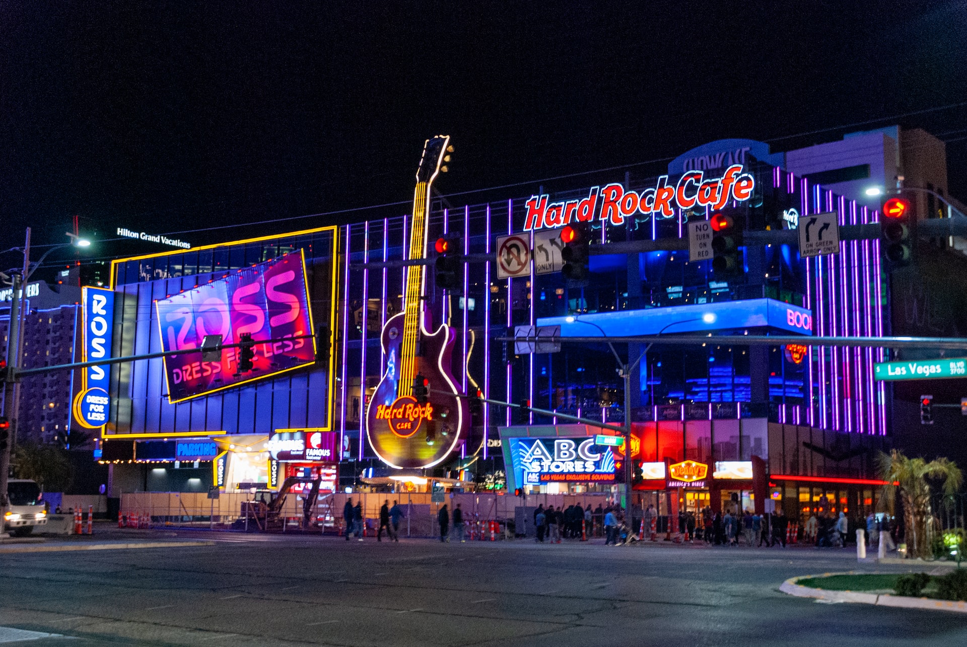a city street at night with neon signs and a guitar