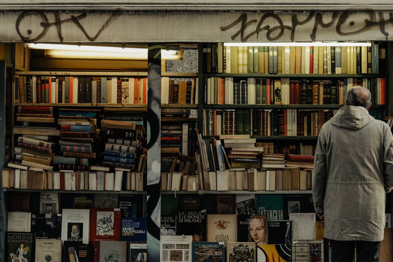 a man standing in front of a bookshelf filled with books