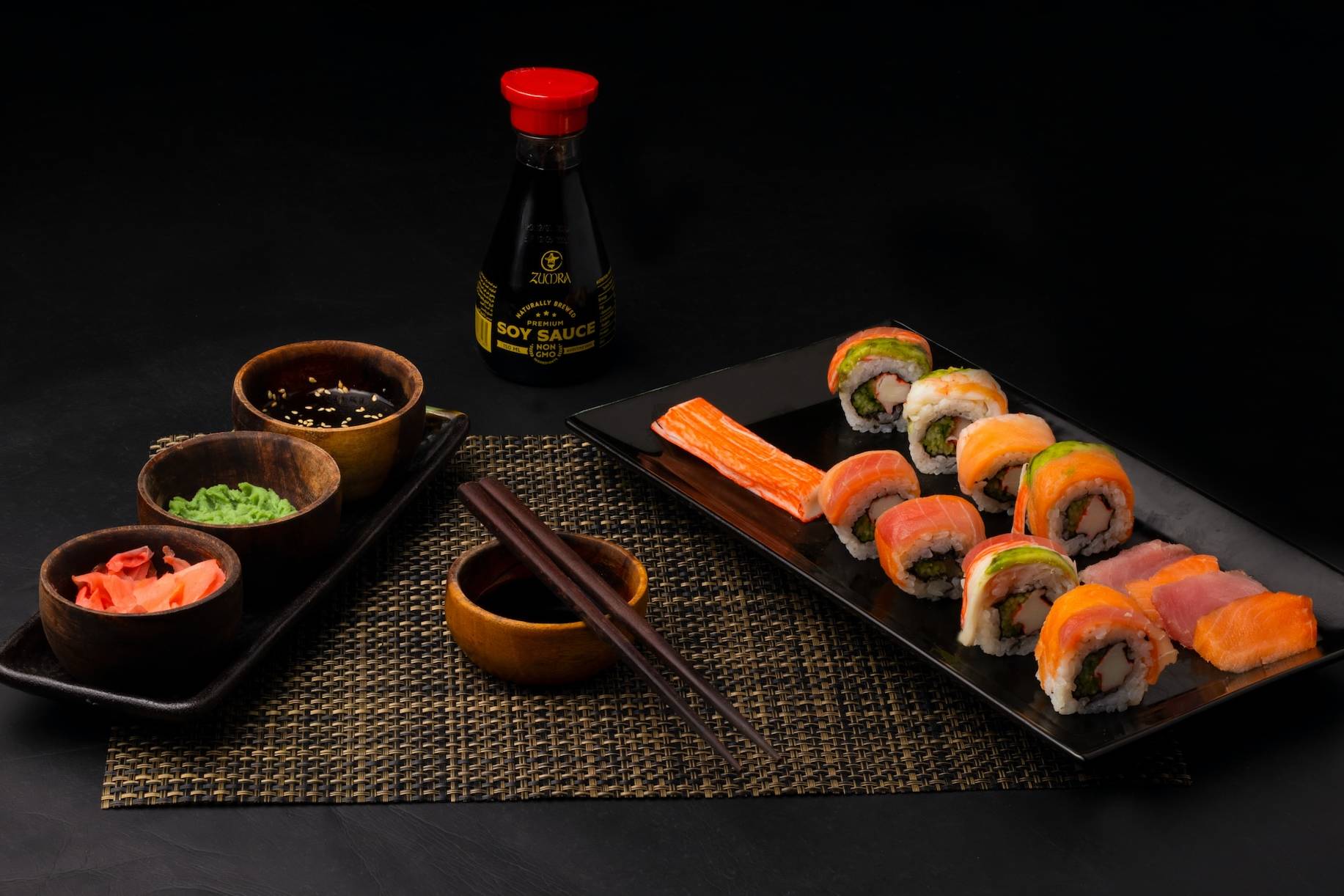 sushi on black ceramic plate beside sauce bottle