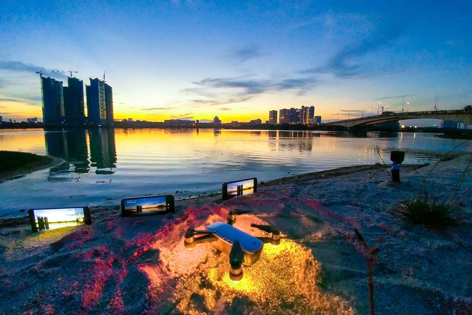 body of water near bridge and city buildings during sunset