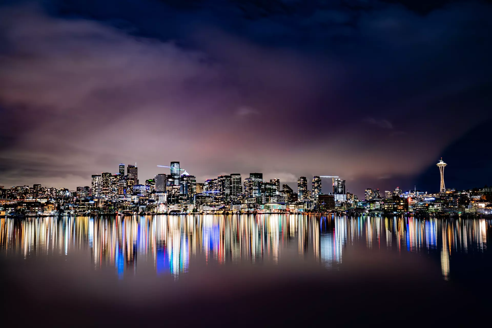 city skyline across body of water during night time